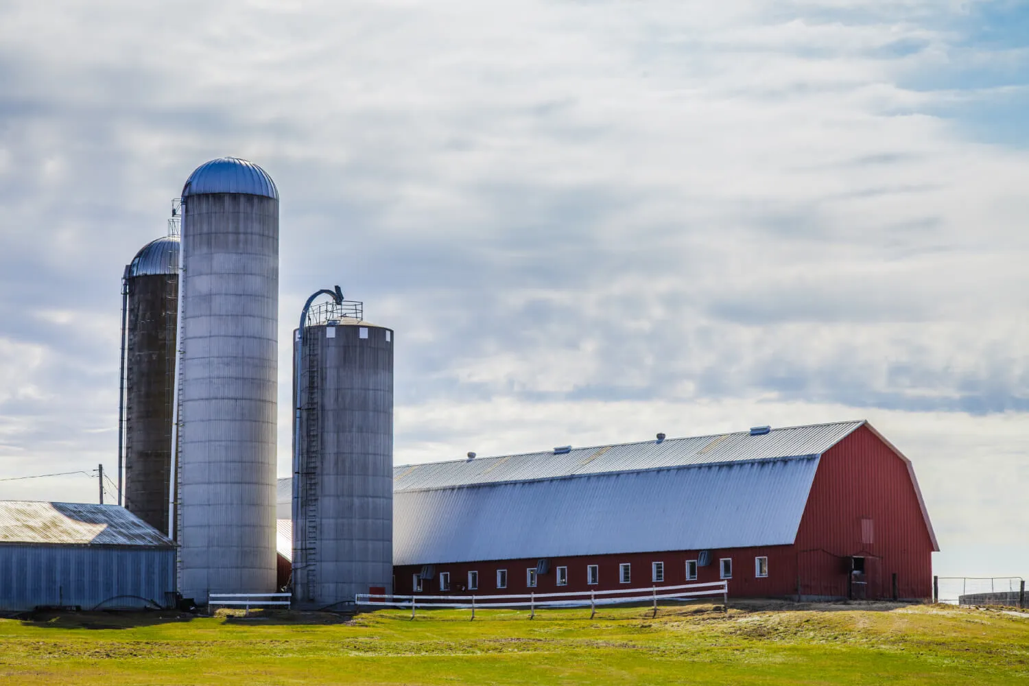 Rural farm with silos and a red barn.